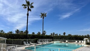 A clear blue sky, a swimming pool with white lounge chairs, and tall palm trees. - Nice studio with balcony located in Fréjus. (Fréjus)