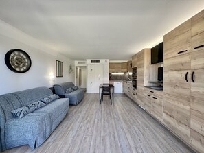 Cozy living space with a sofa, kitchenette, and modern decor.