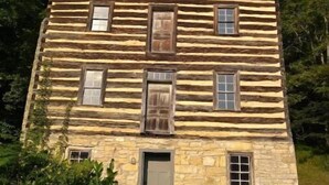 A log cabin with a stone foundation, multiple windows, and a door. - Charming cabin overlooking river Smoky mountains (Chuckey)