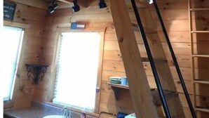 A wooden cabin interior with a loft bedroom, a kitchen area with a sink, and a window providing natural light. - Charming cabin overlooking river Smoky mountains (Chuckey)