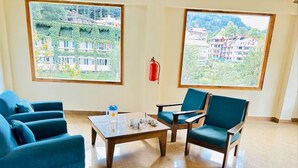 A room with two large windows, a fire extinguisher, and a table with chairs.