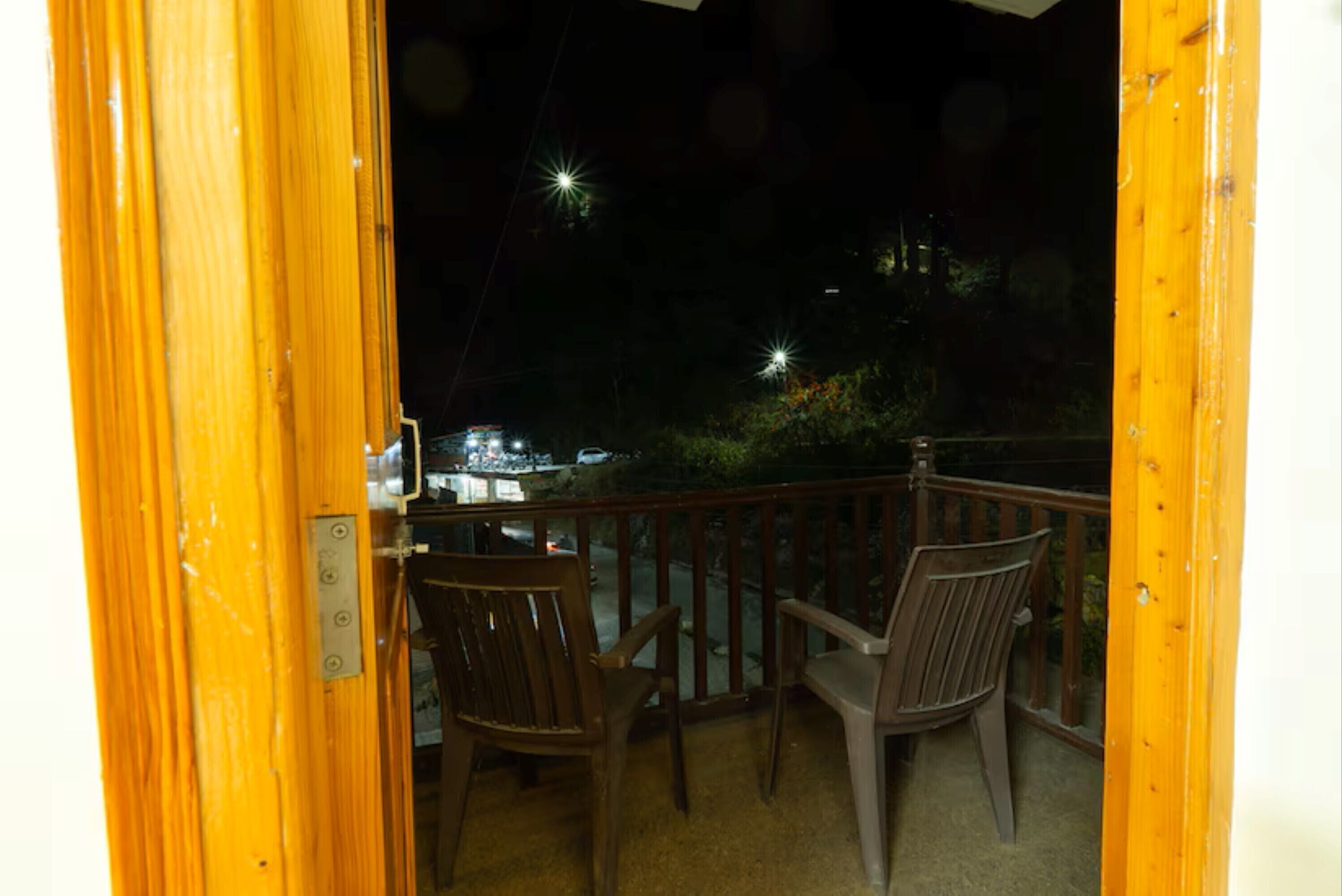A balcony with two wooden chairs and a railing.