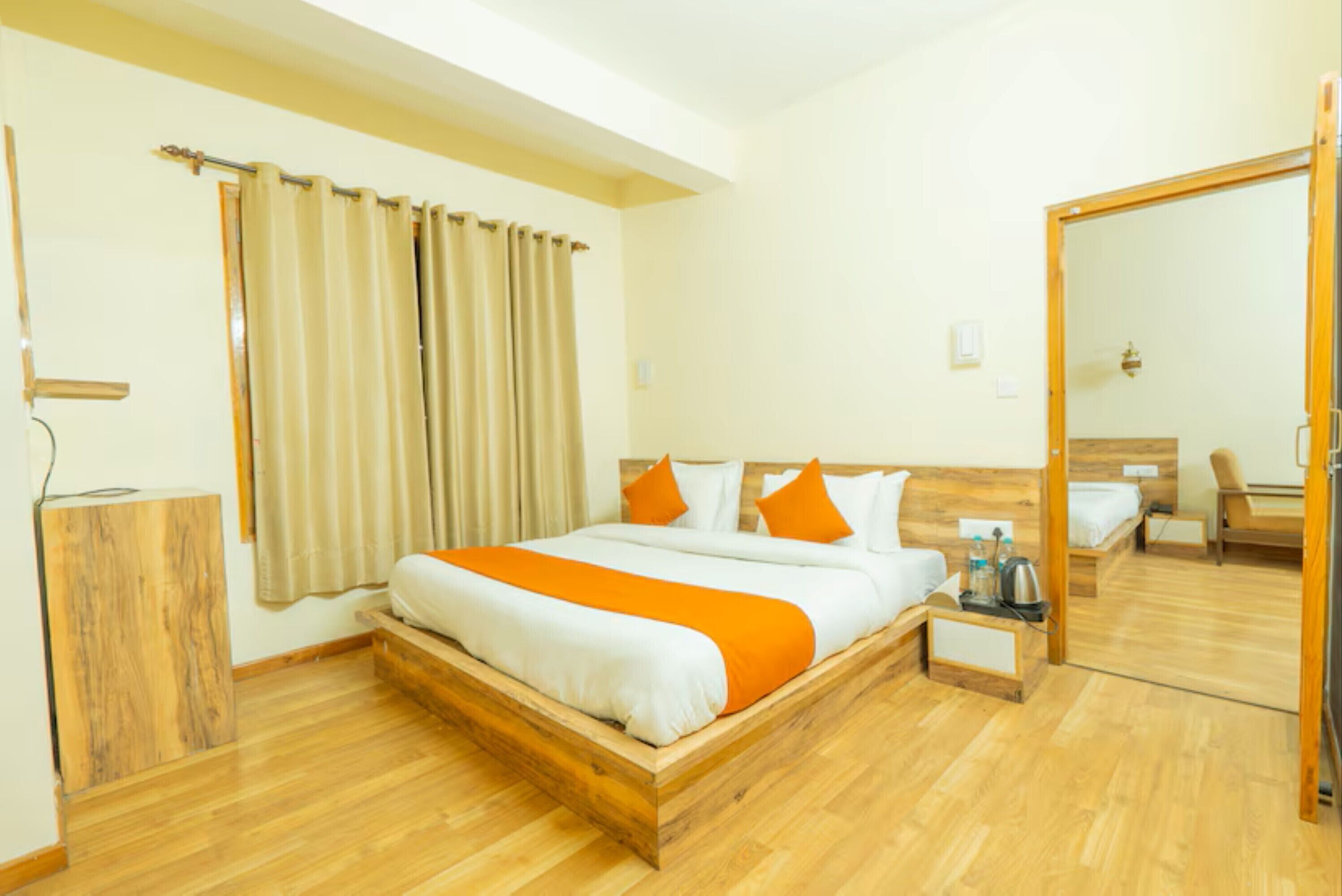 A hotel room with a wooden bed, a wooden nightstand, a mirror, and a wooden wardrobe.