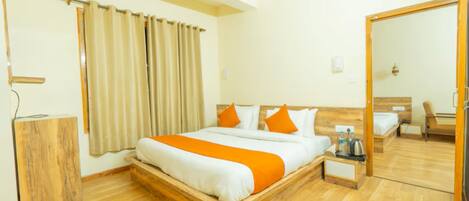 A hotel room with a wooden bed, a wooden nightstand, a mirror, and a wooden wardrobe.