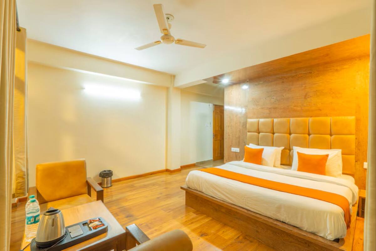 Una habitación de hotel con una cama grande, un escritorio con hervidor y una silla.