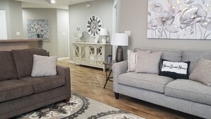 A living room with two sofas, a decorative clock, and a floral painting. - Celebrate Branson (Branson)