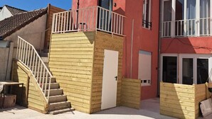 A two-story building with a wooden staircase, a balcony with a white railing, and a large umbrella. - Appartement 6 Personnes Berck, à 400 Mètres de la Plage! (Berck)