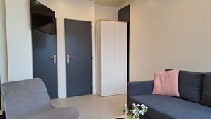 A modern living room with a grey sofa, a grey armchair, a wooden coffee table, a small potted plant, and a black remote control. - Appartement 6 Personnes Berck, à 400 Mètres de la Plage! (Berck)