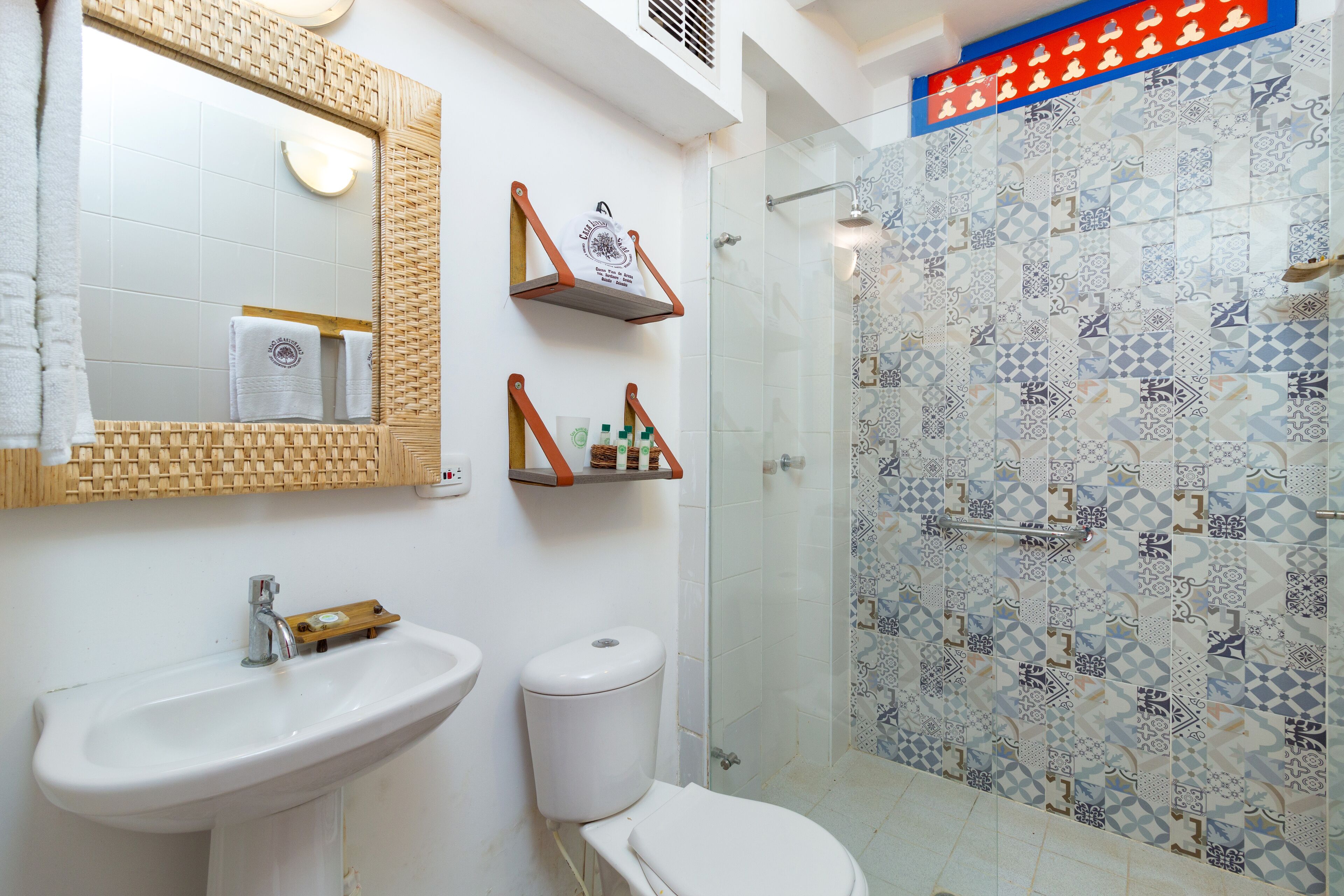 Une salle de bain équipée d’un lavabo, de toilettes et d’une zone de douche avec des carreaux décoratifs.