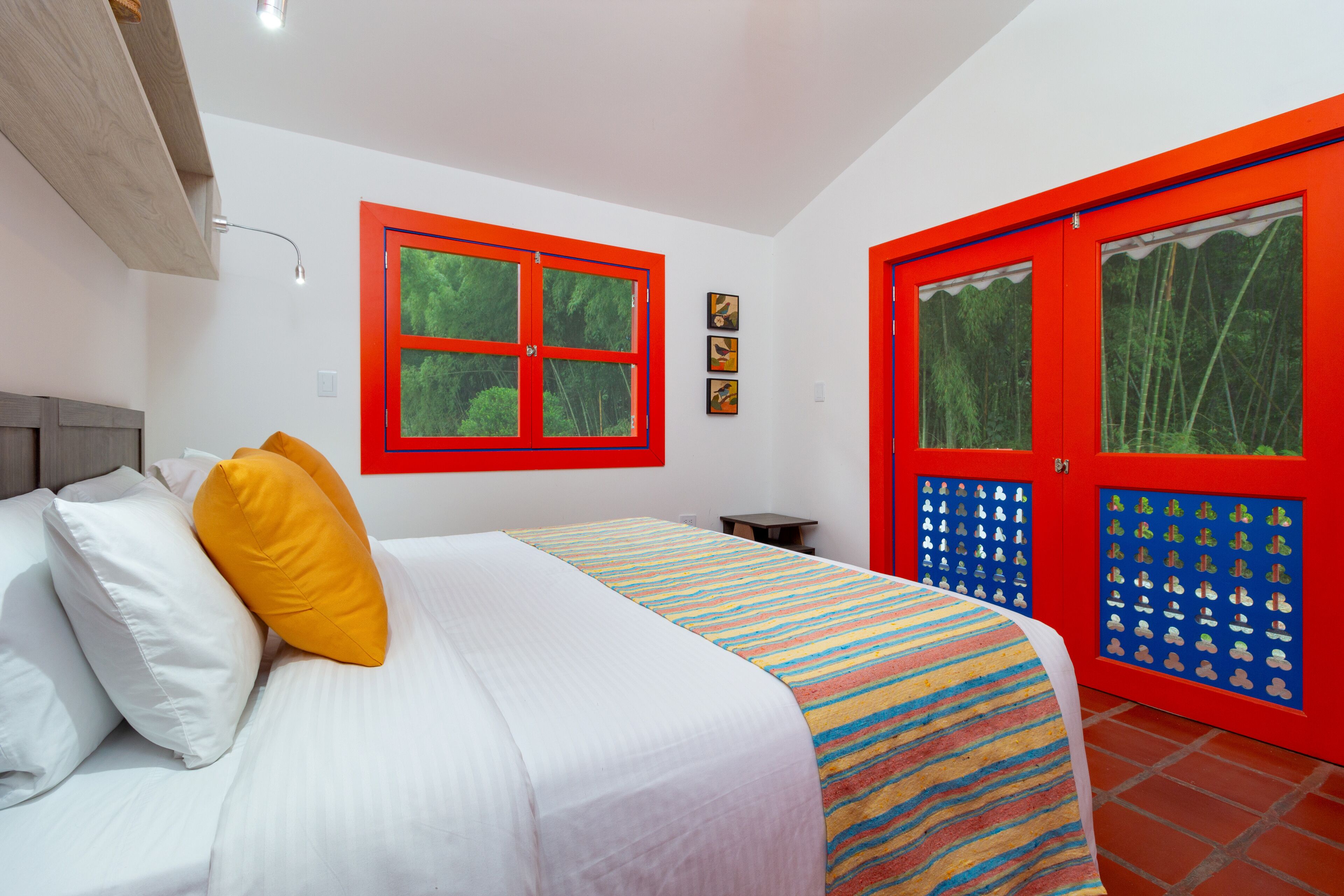 A bedroom with a bed, a window, and a door with a red frame.
