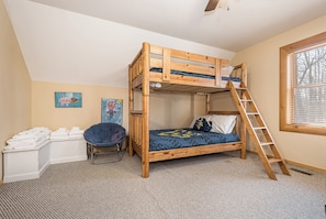 Une chambre avec un lit superposé, une échelle, un bureau avec une chaise et des œuvres d’art accrochées au mur.