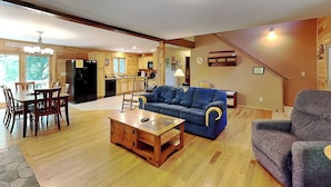 A spacious living area with a dining table, blue sofa, and a grey armchair. - Crazy Idea by Taylor Made Deep Creek (McHenry)