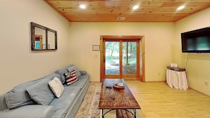 A living room with a sofa, a wooden table, a television, and a door leading outside. - Crazy Idea by Taylor Made Deep Creek (McHenry)