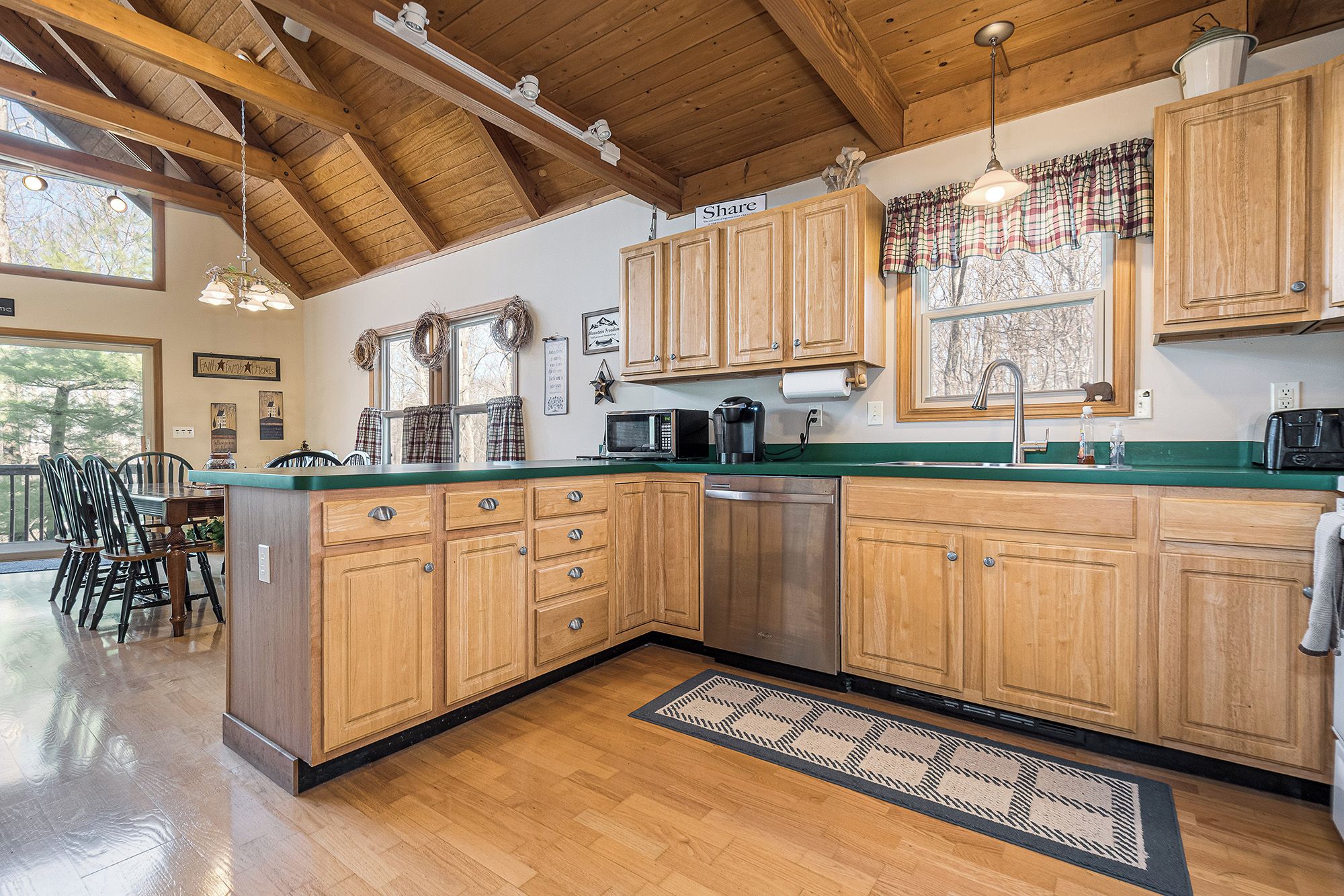 Una cocina amplia con armarios de madera, lavavajillas de acero inoxidable y encimera verde.