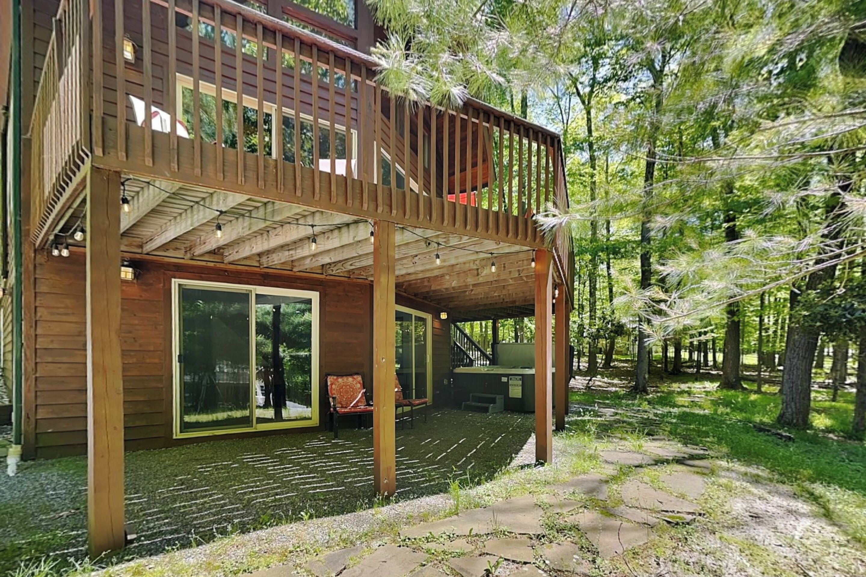 A wooden deck with a covered area, large sliding glass doors, and a seating arrangement.