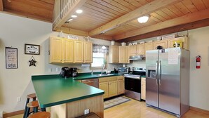 A kitchen with wooden cabinets, a stainless steel refrigerator, a microwave, and a coffee maker. - Mountain Freedom by Taylor Made Deep Creek (Oakland)