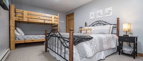Un dormitorio con literas, una cama individual, una mesita de noche, una lámpara y una pared decorada con citas motivacionales.