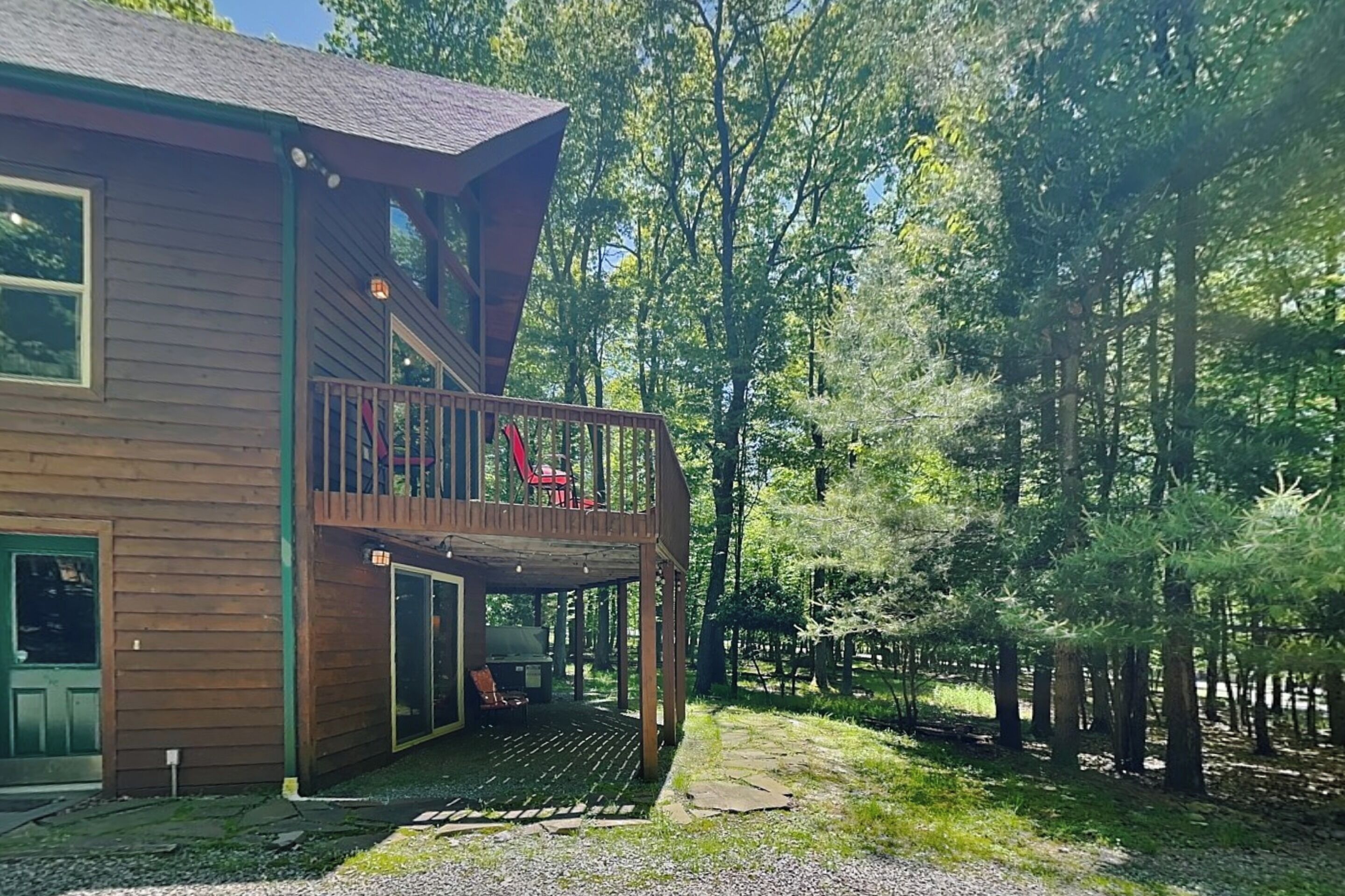 Een houten chalet met twee verdiepingen en een balkon, omgeven door bomen.