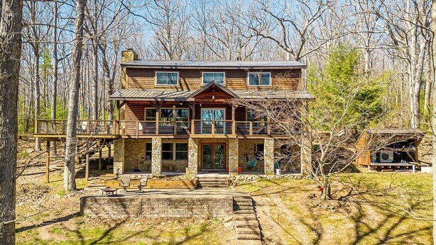 A two-story log cabin with a stone foundation, a balcony, and a small deck area. - Lake Time by Taylor Made Deep Creek (Swanton)