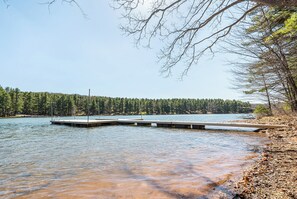 A lake with a dock extending into the water, surrounded by dense forest. - Lake Time by Taylor Made Deep Creek (Swanton)