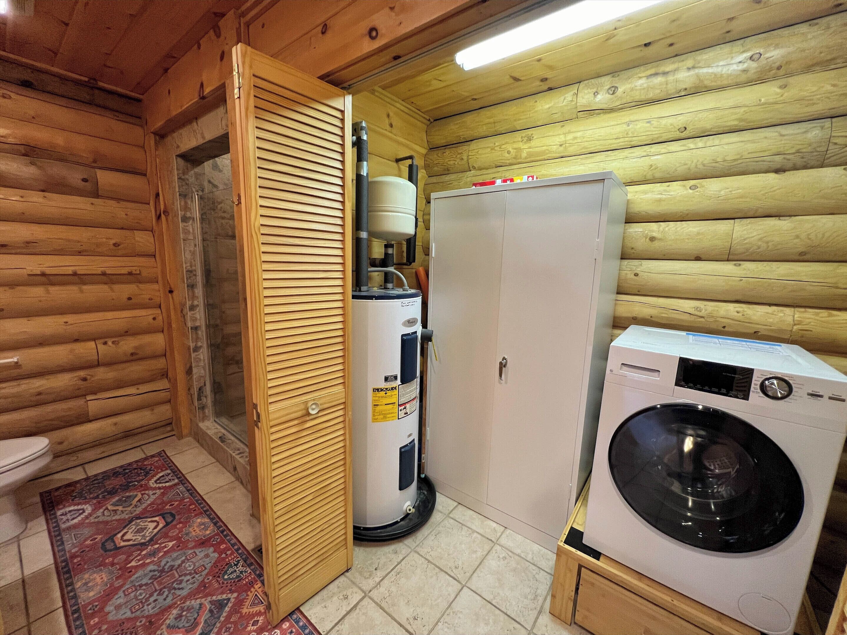 A compact bathroom with a wooden interior, a toilet, a washing machine, and a water heater.