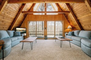 An attic room with a wooden ceiling, two sofas, a table, and a TV. - A Frame of Mind by Taylor Made Deep Creek (McHenry)