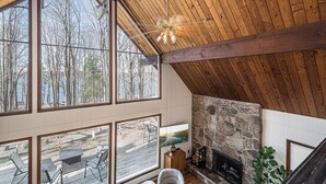 A spacious room with large windows, a stone fireplace, and a wooden ceiling. - Blue Horizon by Taylor Made Deep Creek (Swanton)