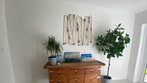 A wooden dresser with multiple drawers, a potted plant, and two framed artworks on top. - Centrally located 5 bedroom house with parking (Miami)