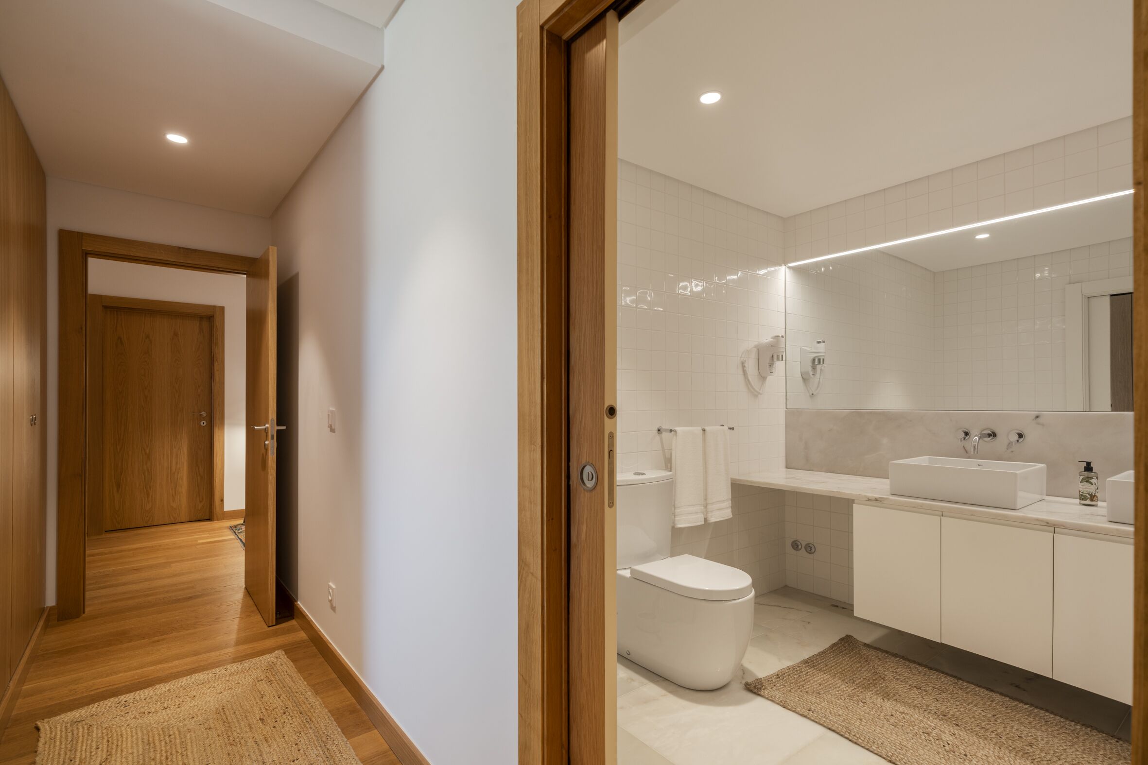 A modern bathroom with a toilet, sink, and mirror.
