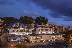 Un hotel moderno con piscina en la azotea, ventanas amplias y vistas de la ciudad.