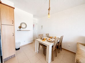 Un coin repas avec une table dressée pour quatre personnes, un buffet en bois et un luminaire suspendu.