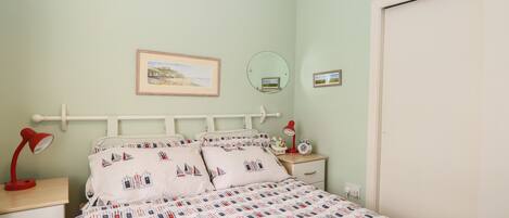 Une chambre à coucher avec un lit, des tables de chevet, un miroir et une porte.