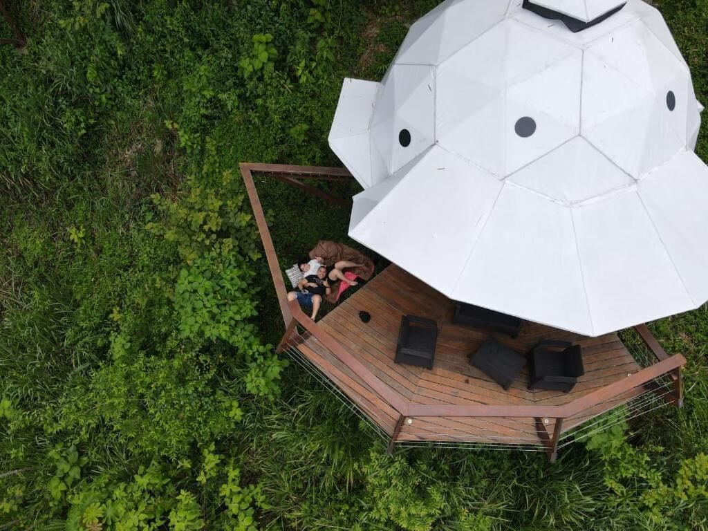 A geodesic dome structure with a wooden deck and seating area.