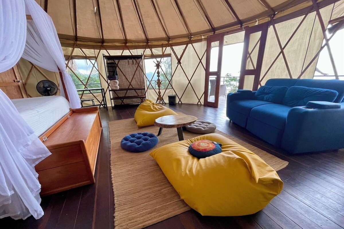 A tent with a bed, a blue sofa, and yellow bean bags.