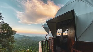 Una terraza de madera con vistas a colinas verdes y un cielo despejado.