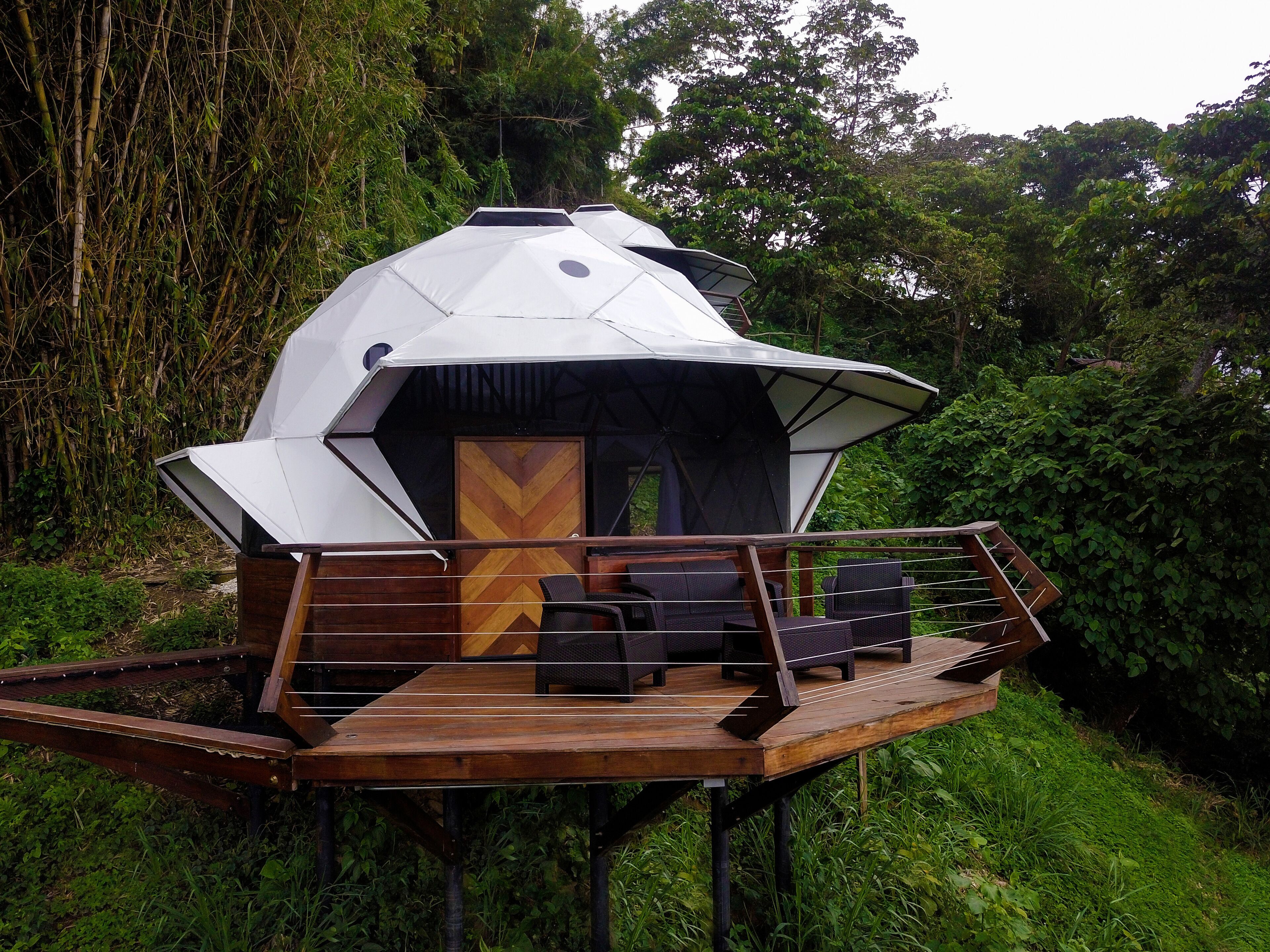 A geodesic dome structure with a wooden deck and outdoor seating area.