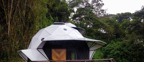A geodesic dome structure with a wooden deck and outdoor seating area.