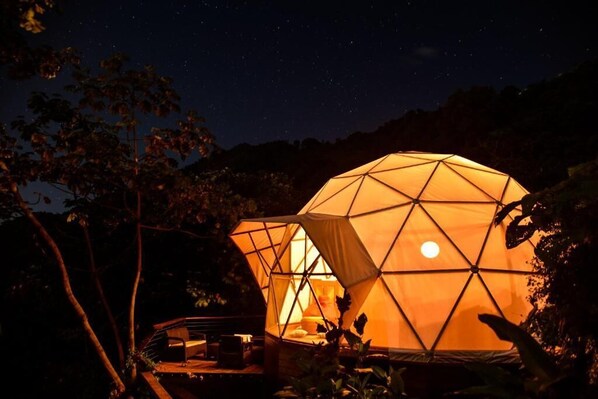 A geodesic dome tent illuminated at night with a view of the moon. - Trekker Glamping (Santa Marta)