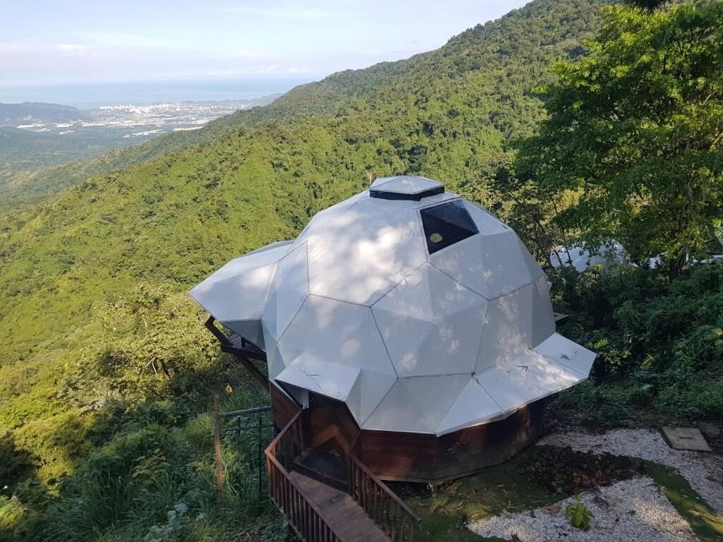 A geodesic dome structure in a mountainous area with a view of the valley below.