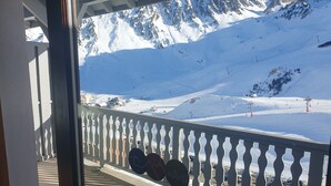 Un balcon avec vue sur une montagne enneigée et des pistes de ski.