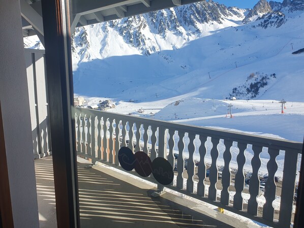 Een balkon met uitzicht op een met sneeuw bedekte berg en skipistes.