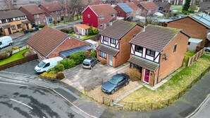 A residential area with houses, a driveway, and parked cars.