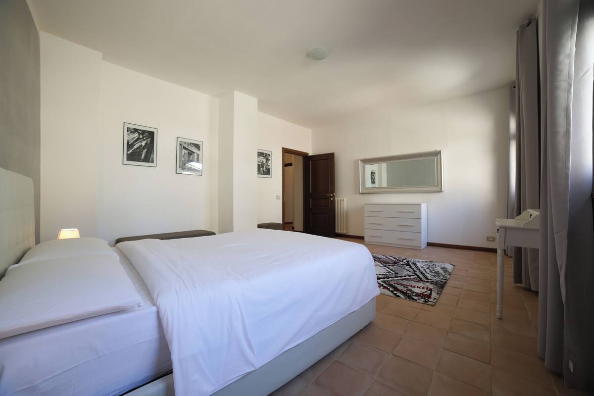 A bedroom with a bed, a dresser, a mirror, and two framed pictures on the wall.