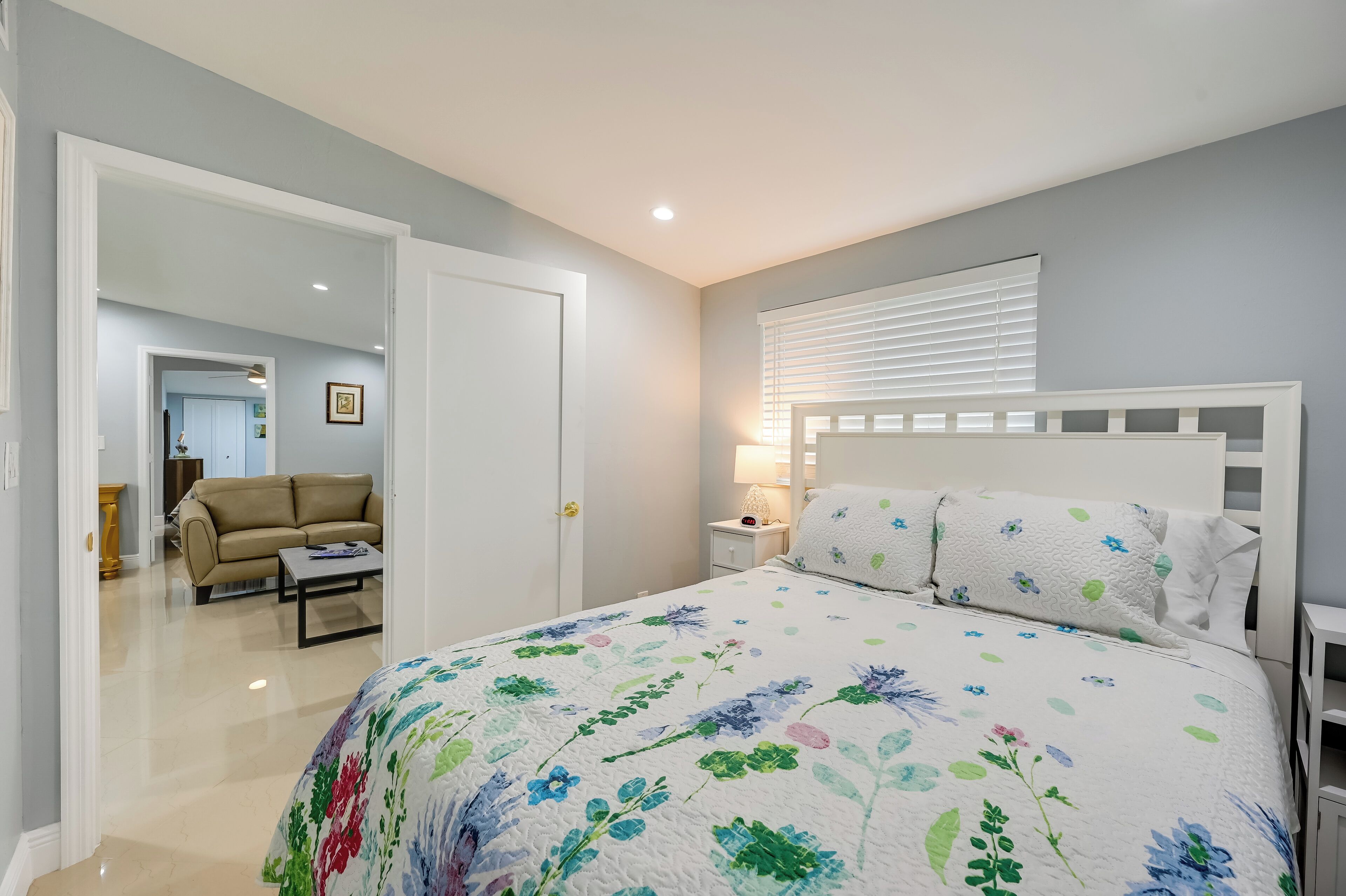 Een slaapkamer met een bloemenbedekking, een wit hoofdeinde en een bedlampje.