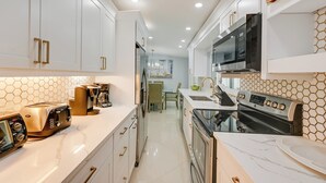 A modern kitchen with white cabinets, a microwave, a toaster, and a coffee maker. - Pelican Nest, Tropical Naples Villa w/ Pool (Naples)
