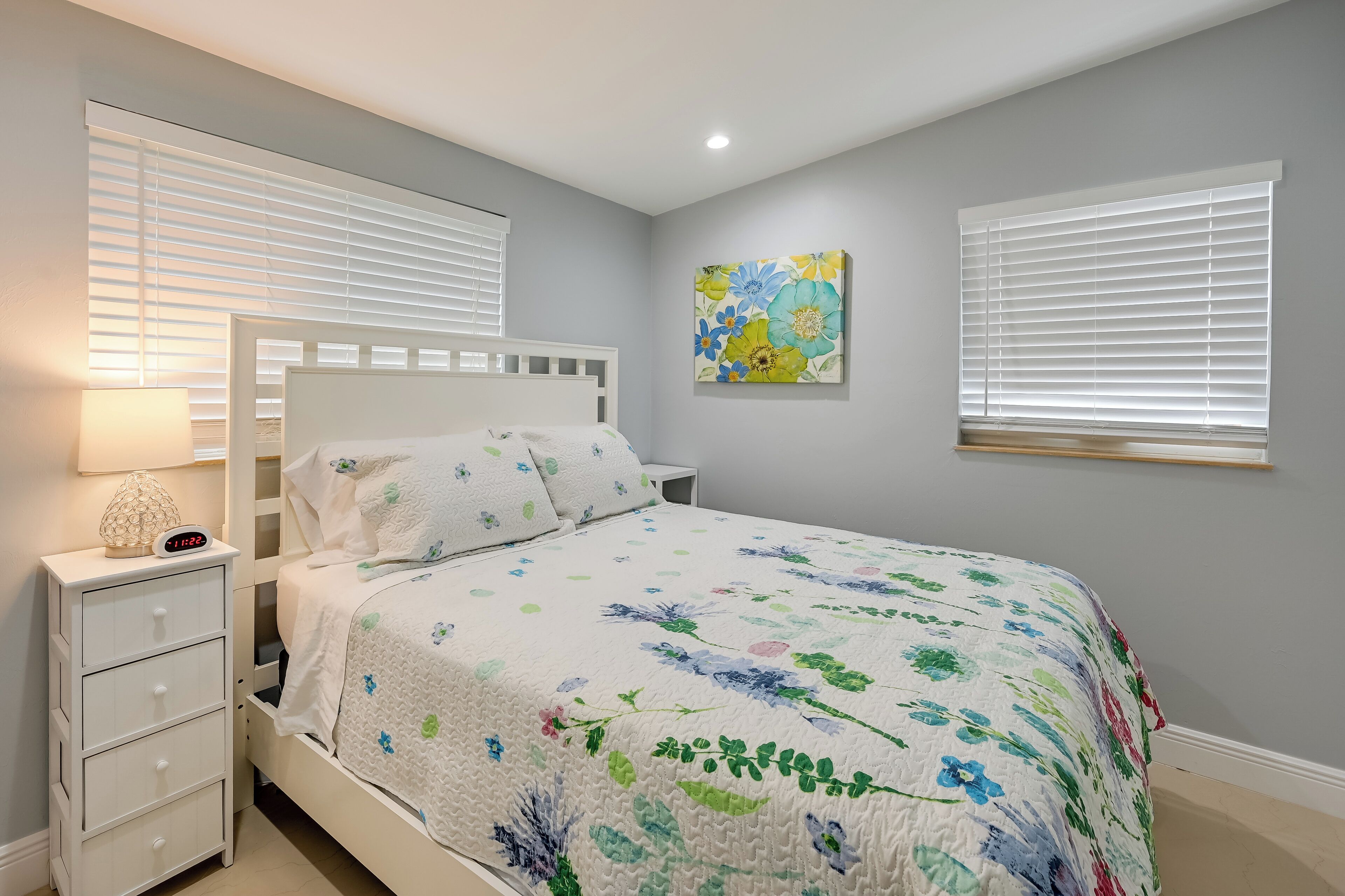 A bedroom with a bed, nightstand, and a wall-mounted painting.