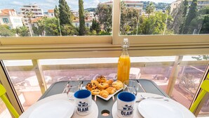 A balcony table set with breakfast items, two mugs, and a bottle of orange juice. - Contemporary 4* 2BR garden view Palais Croisette 5mn Cannes Olam Properties (Cannes)