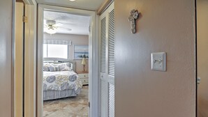 A bedroom with a bed, a nightstand, a lamp, and a ceiling fan. - Beachfront St Petersburg Condo w/ Community Pool! (Treasure Island)