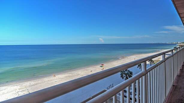 A beach view from a balcony with a railing, clear sky, and calm sea. - Beachfront St Petersburg Condo w/ Community Pool! (Treasure Island)