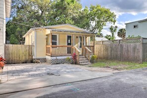 A single-story house with a front porch, a wooden fence, and a paved driveway.